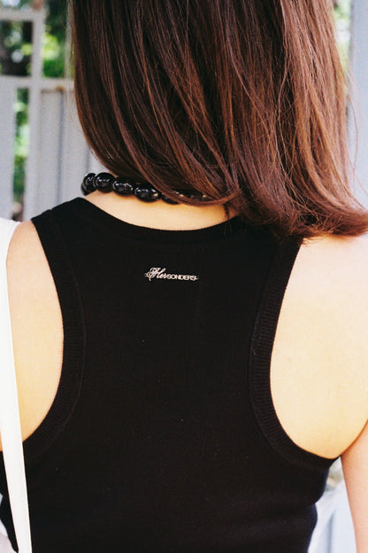 Person wearing a black tank top with a brand logo, standing outdoors.